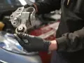 Mechaniker hält ein defektes Motorlager in der Hand, das ausgetauscht werden muss.