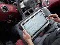Diagnosegerät im luxuriösen Mercedes-Innenraum. Ein Techniker prüft die Daten, um die Service b Mercedes Kosten zu ermitteln.