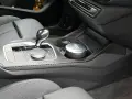 Detailaufnahme des Innenraums eines Autos mit Carbon-Akzenten. Ein Aschenbecher mit Audi-Logo steht im Getränkehalter. So reinigt man klavierlack auto.