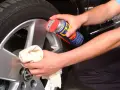 Person reinigt Felgen mit WD-40 und Tuch. Ein Hausmittel für glänzende Felgen.