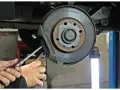 Mechaniker führt eine Inspektion am Bremssattel eines Mercedes durch. Der Service A steht an.