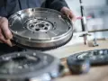 Hände halten ein Zweimassenschwungrad. Die Kosten für ein solches Teil können je nach Marke und Modell variieren.