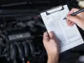 Mechaniker prüft den Motor und füllt ein Formular aus, um die durchsicht auto kosten zu ermitteln.