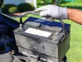 Gefährliche alte Autobatterie wird vorsichtig herausgehoben. Die richtige Entsorgung ist wichtig.