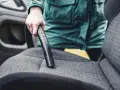 Person reinigt den auto innenraum mit einem Staubsauger.