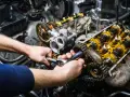 Mechaniker repariert einen Motor. Die Kosten für einen Motorschaden können hoch sein, aber eine Reparatur ist oft möglich.