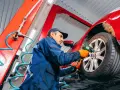 Mechaniker wechselt Reifen an rotem Auto. Informieren Sie sich, was kostet reifenwechsel, um Ihr Fahrzeug sicher zu halten.