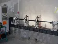 Kardanwelle wuchten auf einer speziellen Maschine. Die Welle ist auf Rollen gelagert, daneben eine Steuereinheit und ein Schweißhelm.