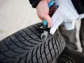 Mit einer Zange wird ein kleiner Nagel aus dem Profil eines Autoreifens entfernt.