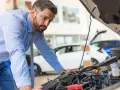 Mann prüft Motor, weil das Auto nicht mehr richtig beschleunigt.