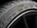 Nahaufnahme eines Autoreifens mit der Kennzeichnung DOT. Der Reifen ist auf einer schwarzen Felge montiert.