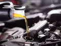 Frisches Öl fließt aus einer Flasche in einen Motor. Die API-Klassifikation des Öls ist entscheidend für die Leistung.