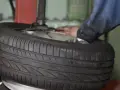 Reifenmontagemaschine mit einem Reifen und einer Hand, die daran arbeitet.