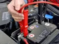 Starthilfe Auto: Rote Klemme wird am Pluspol der Batterie befestigt. Die richtige Reihenfolge ist entscheidend für die Sicherheit.
