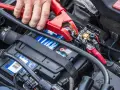 Starthilfe für eine leere Autobatterie: Rote und schwarze Klemmen werden an die Batterie angeschlossen.