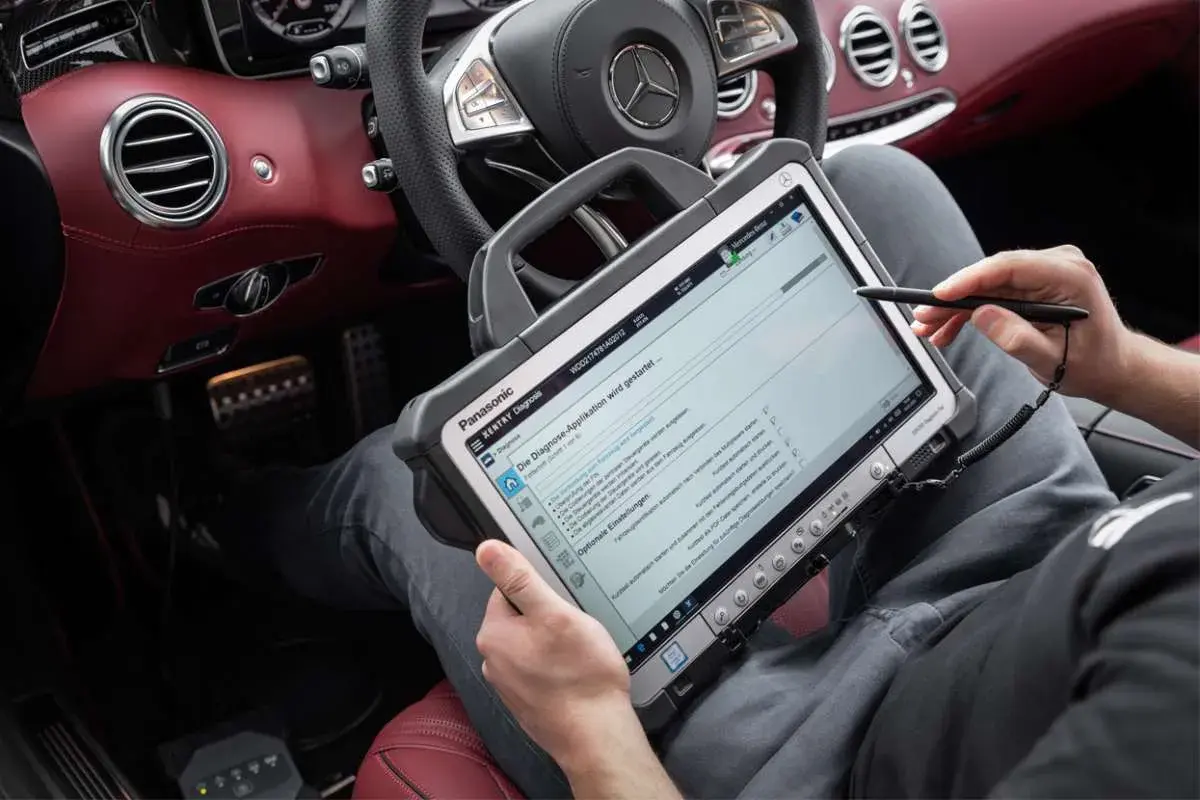 Diagnosegerät im luxuriösen Mercedes-Innenraum. Ein Techniker prüft die Daten, um die Service b Mercedes Kosten zu ermitteln.