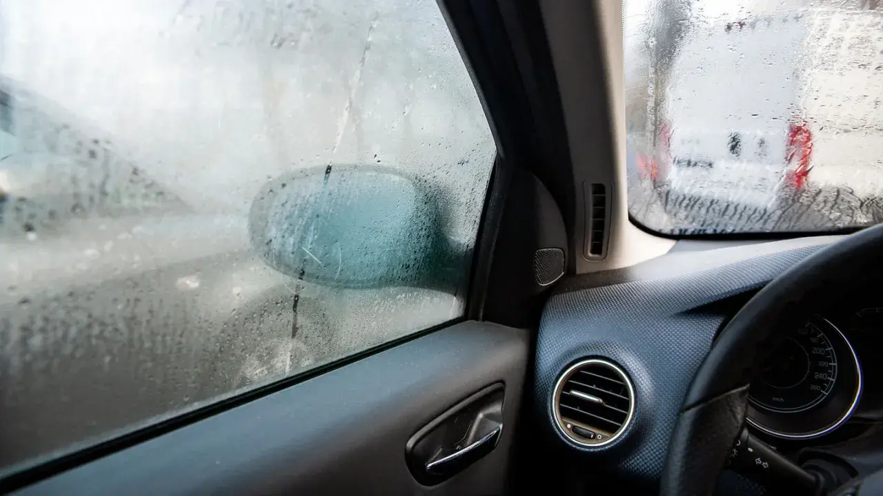 Beschlagene Autoscheiben innen reinigen. Ein Blick aus dem Auto zeigt beschlagene Scheiben und einen Außenspiegel.