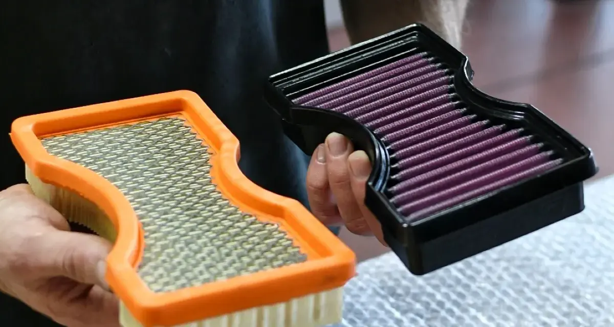 Hände halten zwei Luftfilter: einen orangen Standardfilter und einen schwarzen Sportluftfilter. Was bringt ein Sportluftfilter? Mehr Leistung!