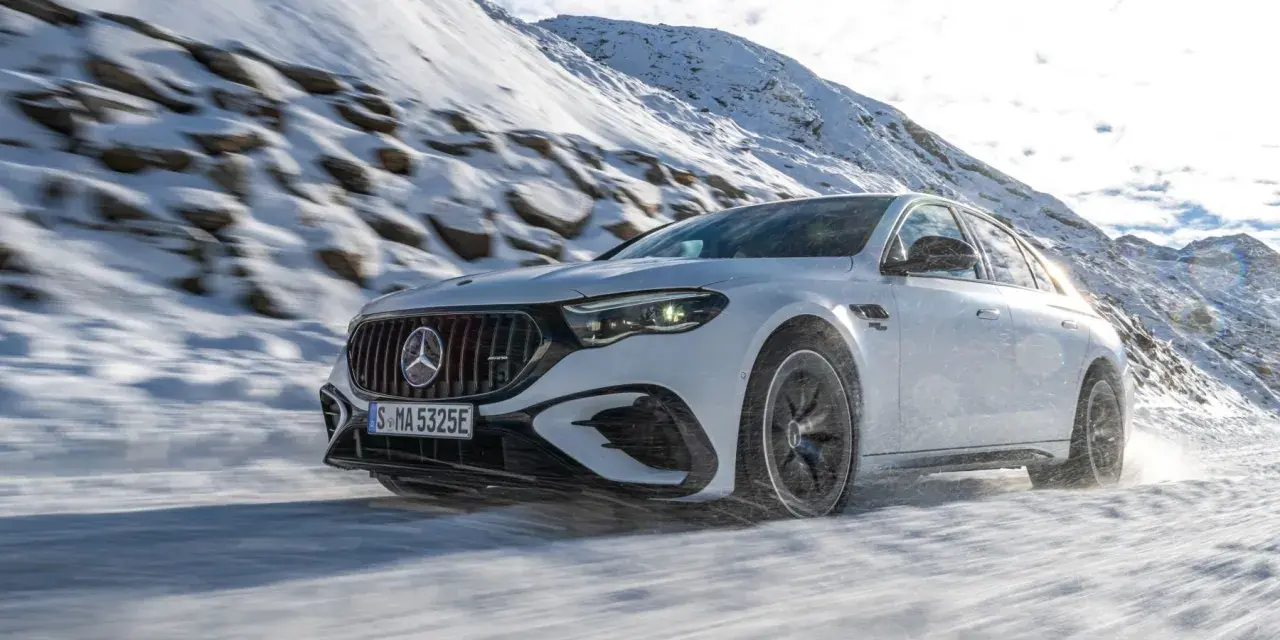 Weißer Mercedes-AMG mit 4MATIC fährt durch verschneite Berglandschaft.