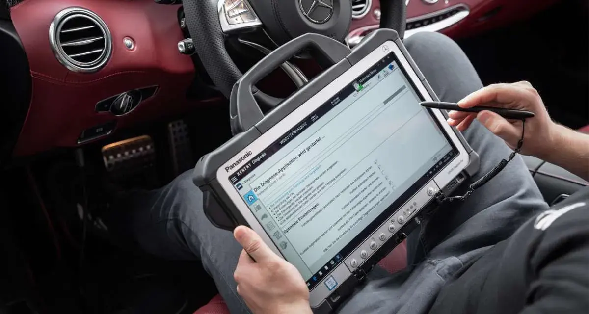 Diagnosegerät im luxuriösen Mercedes-Innenraum. Ein Techniker prüft die Daten, um die Service b Mercedes Kosten zu ermitteln.