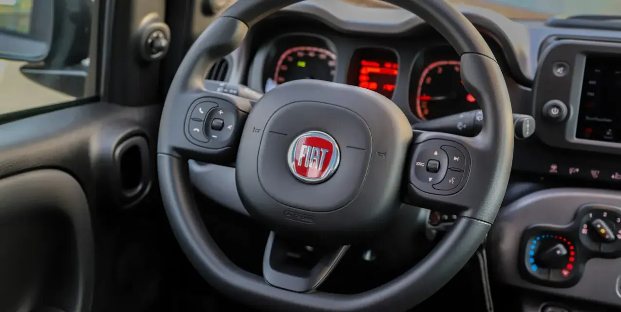 Lenkrad eines Fiat Panda. Die Instrumententafel zeigt rote Warnleuchten, vielleicht für den **Fiat Panda Reifendruck**.