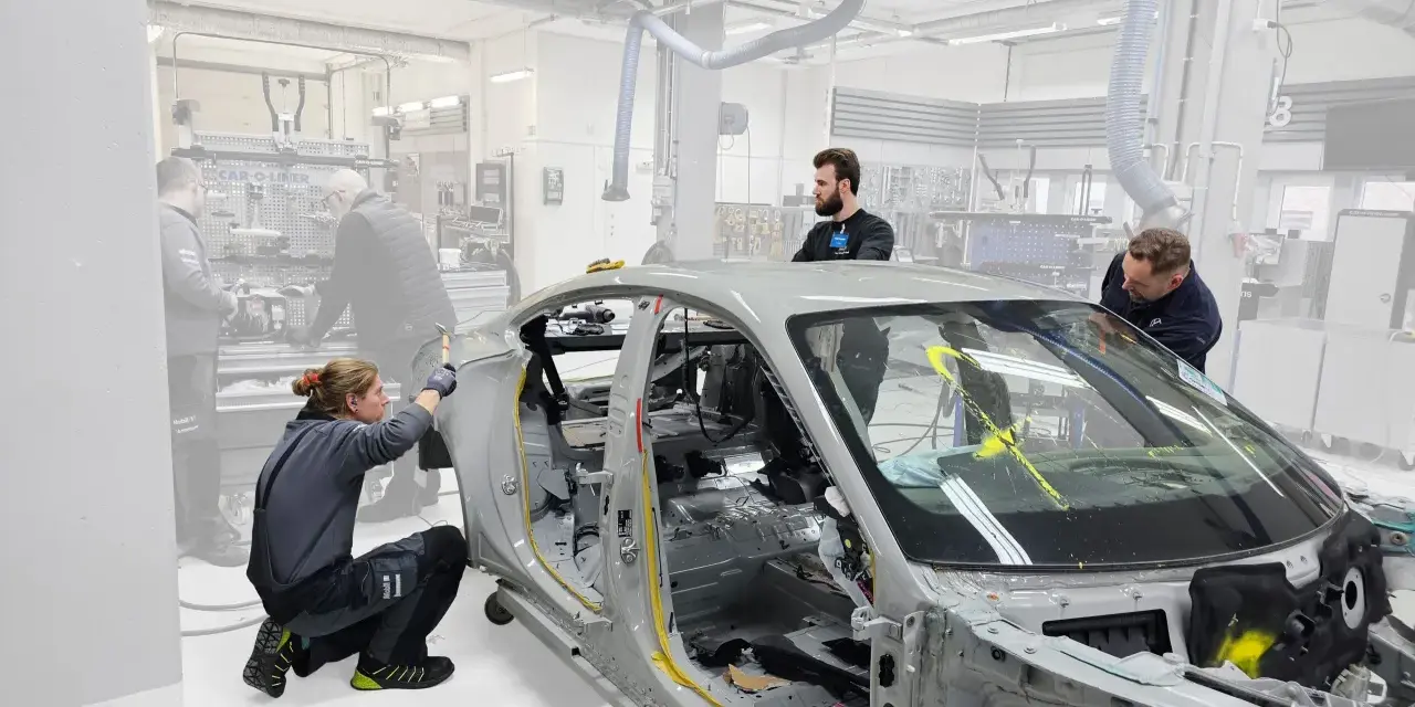 Mitarbeiter arbeiten an einem Auto-Chassis. Sie sind Teil eines Teams, das sich mit der Frage beschäftigt, was OEMs sind und wie sie in der Automobilproduktion eingesetzt werden.