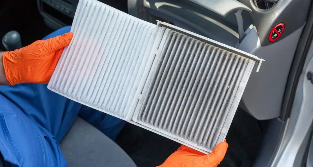 Person mit orangefarbenen Handschuhen hält einen neuen und einen schmutzigen Innenraumfilter. Zeit, den Innenraumfilter zu wechseln für saubere Luft im Auto.