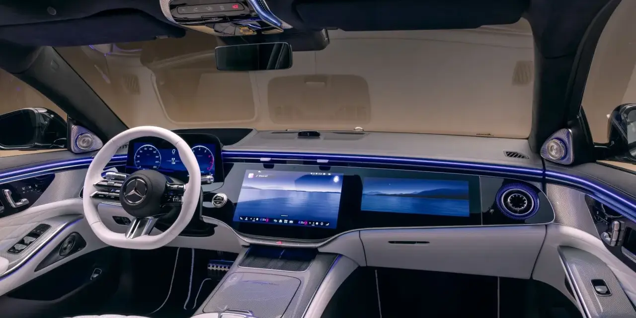 Luxuriöses Auto-Armaturenbrett mit großem Touchscreen, weißem Lenkrad und Ambientebeleuchtung.