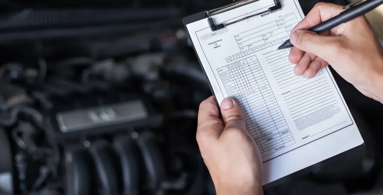 Mechaniker prüft den Motor und füllt ein Formular aus, um die durchsicht auto kosten zu ermitteln.