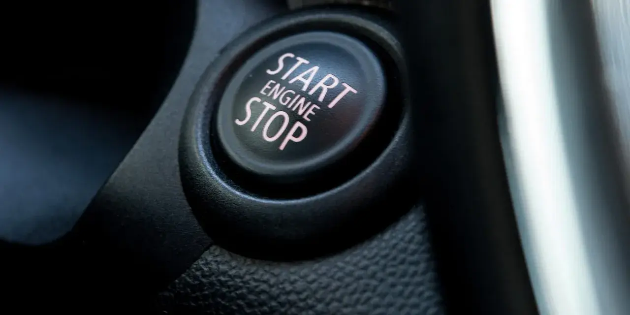 Nahaufnahme eines Start/Stop-Knopfes im Auto. Der Knopf ist beleuchtet und zeigt die Worte "START ENGINE STOP".