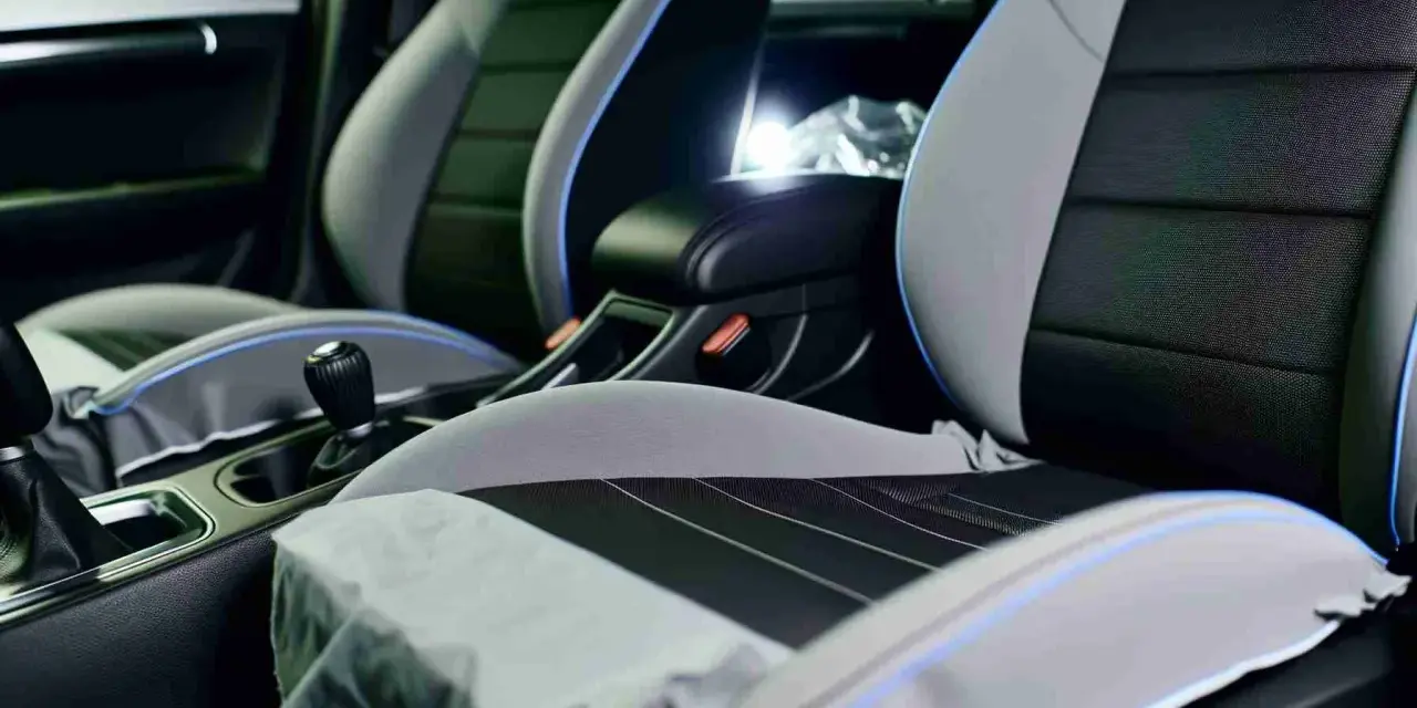Detailaufnahme des Innenraums eines Autos, mit Fokus auf die Sitze. Die Sitze sind zweifarbig, grau und schwarz, mit blauen Akzenten. Sie scheinen bereit für die **ledersitze reparieren** zu sein.