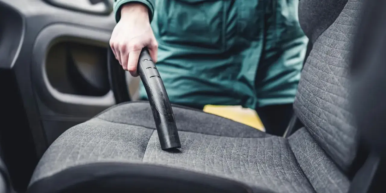 Person reinigt den auto innenraum mit einem Staubsauger.