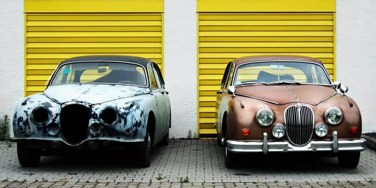 Zwei Oldtimer vor gelben Garagentoren. Einer ist rostig, der andere glänzt. Die **Oldtimer Lackieren Kosten** variieren stark.