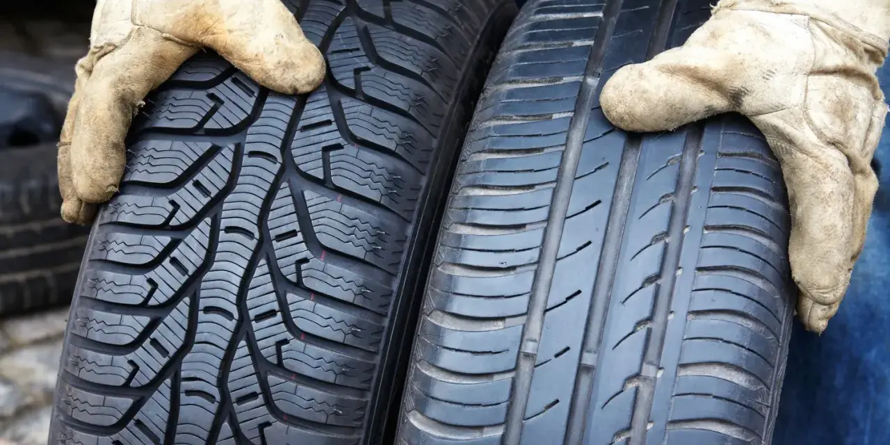 Zwei Reifen werden von Händen in Arbeitshandschuhen gehalten. Links ein Winterreifen, rechts ein Sommerreifen. Darf man mit Winterreifen im Sommer fahren?