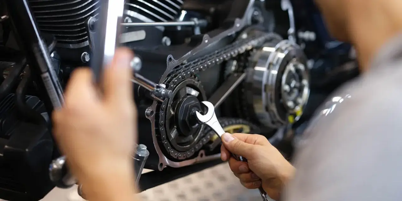 Mechaniker repariert Motorrad-Steuerkette. Die Kosten für den Wechsel der Steuerkette sind hier ein wichtiger Faktor.