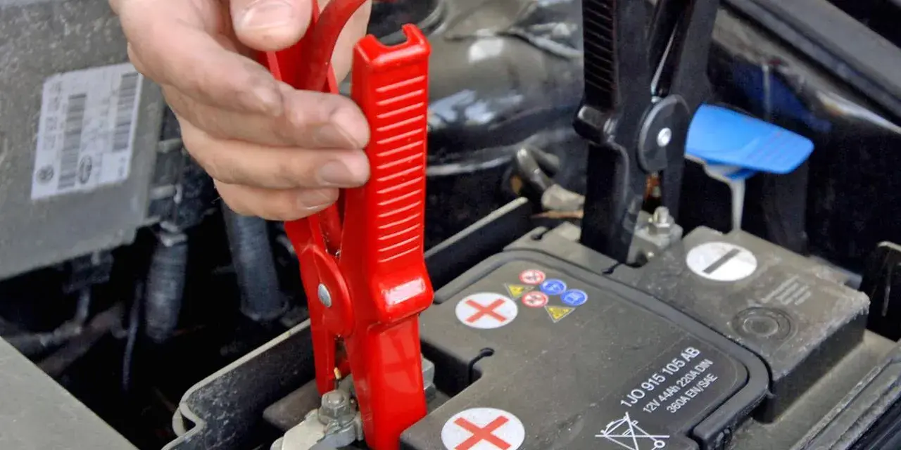 Starthilfe Auto: Rote Klemme wird am Pluspol der Batterie befestigt. Die richtige Reihenfolge ist entscheidend für die Sicherheit.