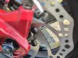 Nahaufnahme einer roten Bremse und einer gelochten Bremsscheibe. Ein ABS-System bietet Vorteile wie verbesserte Kontrolle und kürzere Bremswege.