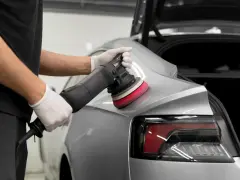 Detailarbeit beim **Lack polieren Auto**. Ein Mann mit Handschuhen nutzt eine Poliermaschine, um den glänzenden Lack auf Hochglanz zu bringen.