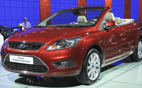 Roter Ford Focus Coupé-Cabriolet auf einer Messe. Ein Blick auf den **Ford Focus Wartungsplan** hilft, diesen Wagen in Topform zu halten.