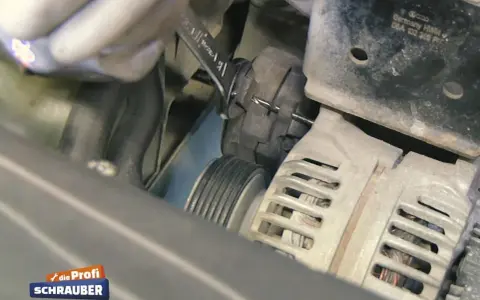 Werkzeug wird benutzt, um den Keilriemen zu spannen. Ein Keilriemen ist ein wichtiger Bestandteil des Motors.