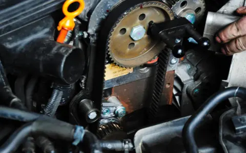 Ein Mechaniker arbeitet am Zahnriemenwechsel. Wann ist der richtige Zeitpunkt dafür?