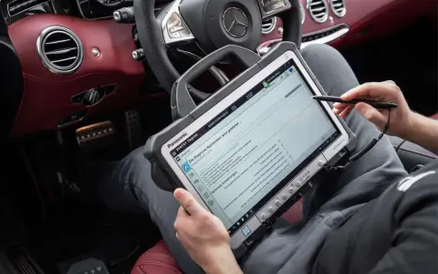 Diagnosegerät im luxuriösen Mercedes-Innenraum. Ein Techniker prüft die Daten, um die Service b Mercedes Kosten zu ermitteln.