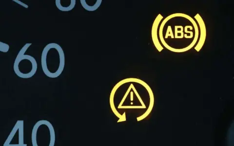 Gelbe Kontrollleuchten im Auto: ABS-Symbol und allgemeines Warnsymbol. Vorsicht ist geboten.