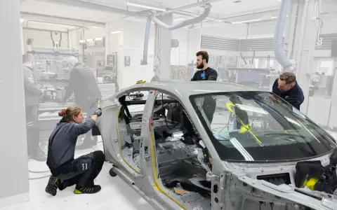 Mitarbeiter arbeiten an einem Auto-Chassis. Sie sind Teil eines Teams, das sich mit der Frage beschäftigt, was OEMs sind und wie sie in der Automobilproduktion eingesetzt werden.