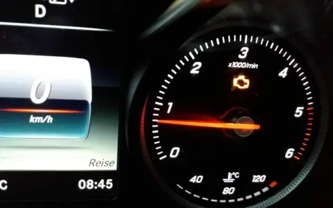 Mercedes-Armaturenbrett mit leuchtender Motorkontrollleuchte. Tachometer zeigt 0 km/h, daneben die Uhrzeit 08:45.