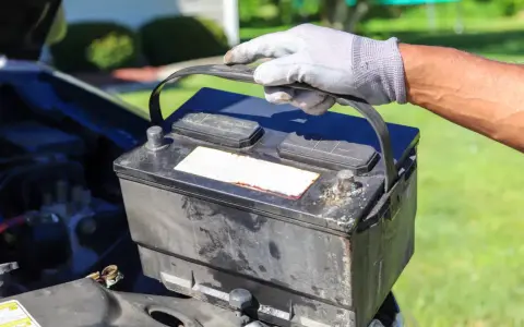 Gefährliche alte Autobatterie wird vorsichtig herausgehoben. Die richtige Entsorgung ist wichtig.