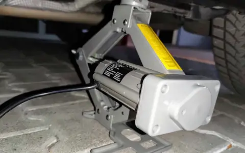 Elektrischer Wagenheber hebt das Auto an, um Reifen mit Reifendrucksensor selber zu wechseln.