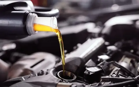 Frisches Öl fließt aus einer Flasche in einen Motor. Die API-Klassifikation des Öls ist entscheidend für die Leistung.