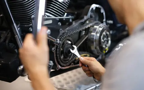 Mechaniker repariert Motorrad-Steuerkette. Die Kosten für den Wechsel der Steuerkette sind hier ein wichtiger Faktor.