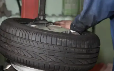 Reifenmontagemaschine mit einem Reifen und einer Hand, die daran arbeitet.